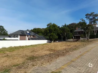 Vista externa de uma propriedade com campo gramado e muro de divisa.
