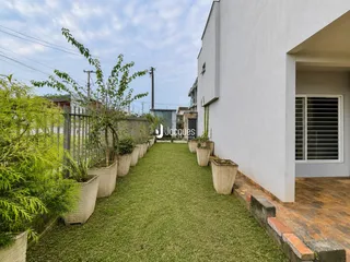 Fachada de uma casa com jardim gramado e vasos de plantas ao longo de uma cerca.