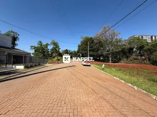 Vista externa da propriedade mostrando a entrada com uma estrada de terra e vegetação ao fundo.