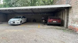 Vista externa de uma garagem coberta com dois veículos estacionados.