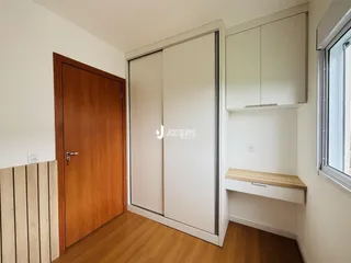 Interior de um ambiente com piso de madeira e armários brancos.