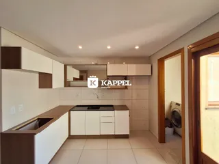 Cozinha moderna com armários brancos e bancada escura.