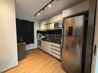 Cozinha moderna com armários brancos e piso de madeira clara.