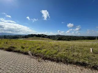 Vista panorâmica de paisagem rural com colinas verdes sob um céu azul claro.