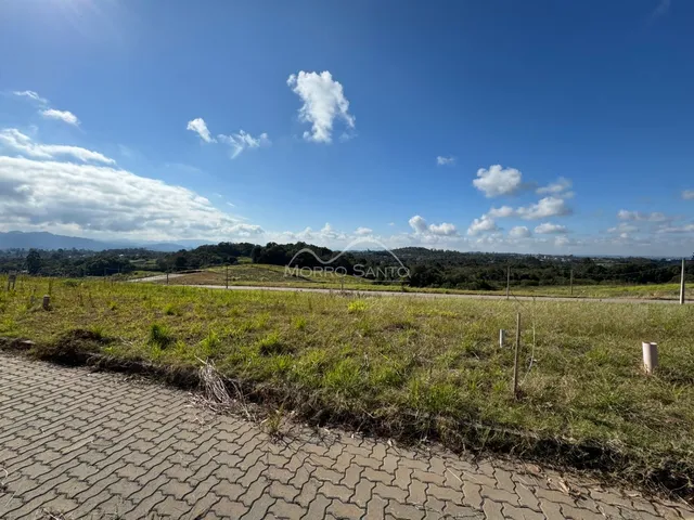 Vista panorâmica de paisagem rural com colinas verdes sob um céu azul claro.