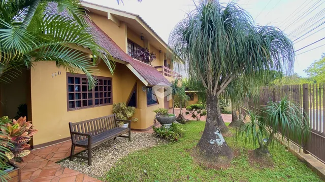Fachada de uma casa em Lajeado, Brasil com jardim e banco de madeira.