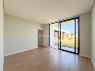 Sala de estar com piso de madeira e porta de vidro que dá para o jardim.