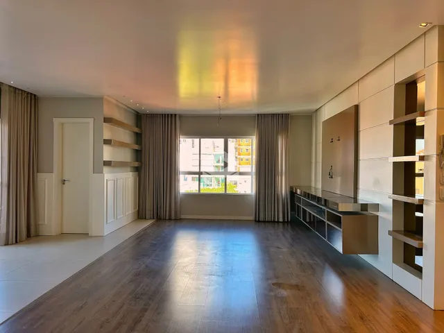 Sala de estar ampla com piso de madeira e grandes janelas.