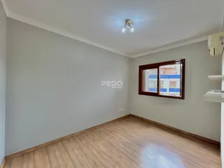 A foto mostra uma sala de estar com piso de madeira clara e paredes cinzas.