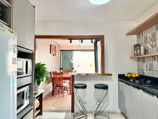 Interior de uma sala de estar com passagem para uma área de jantar.