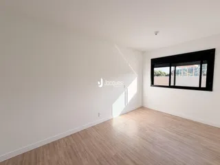 Uma sala com piso de madeira clara e grande janela.