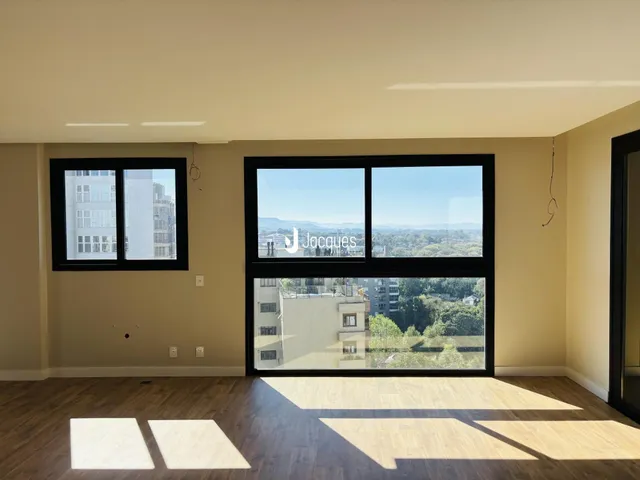 Sala de estar com piso de madeira e grande janela com vista para a paisagem.