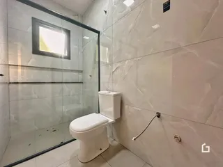 Interior de um banheiro com box de vidro e vaso sanitário branco.
