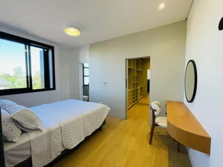 Quarto com piso de madeira e grande janela.