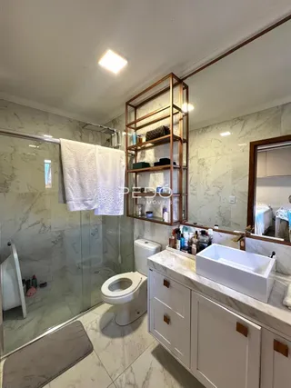Banheiro com piso de cerâmica e box de vidro em um imóvel em Lajeado.