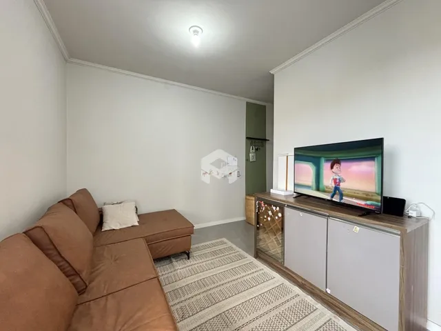 Sala de estar com sofá e televisão em um ambiente claro.