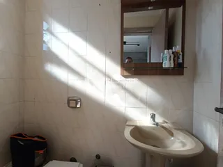 Foto de um banheiro com paredes de azulejo branco e espelho.