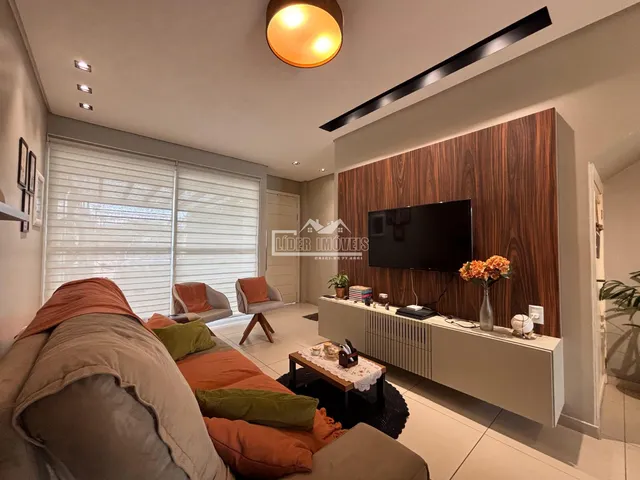 Sala de estar com sofá grande e televisão em parede de madeira.