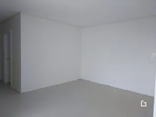 Ambiente interno de uma sala vazia com paredes brancas.