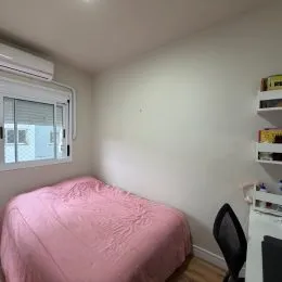Foto de um quarto com cama coberta por um edredom rosa.