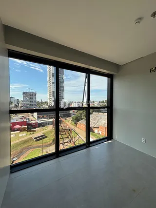 Vista da sala de estar com grande janela para uma área externa industrial.