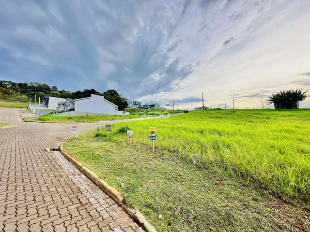 Vista externa de uma propriedade com terreno gramado e edificações ao fundo.