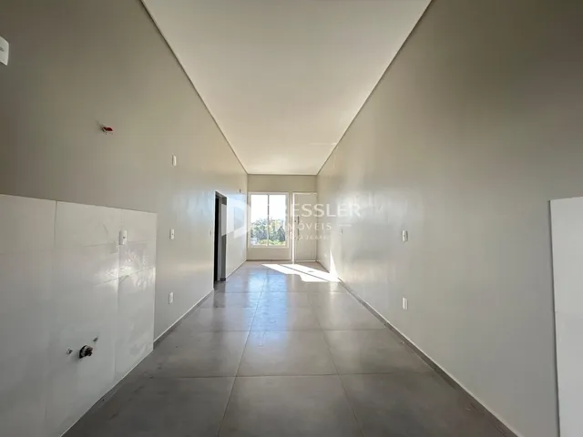 Corredor interno de uma residência com paredes brancas e piso claro.
