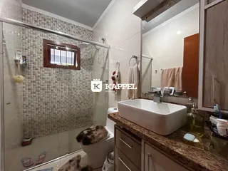 Banheiro com box de vidro e bancada de granito.