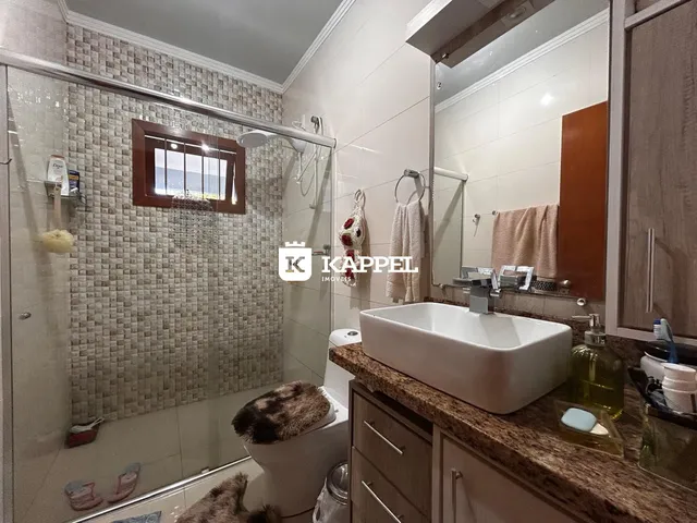 Banheiro com box de vidro e bancada de granito.
