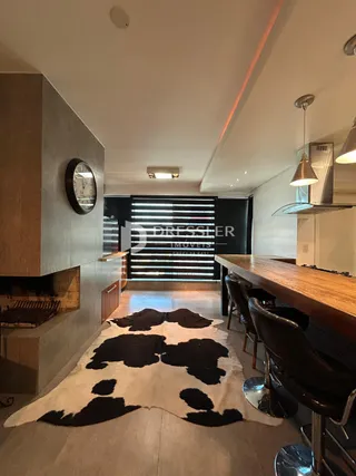 Interior de uma sala de jantar com piso de madeira e mesa grande.