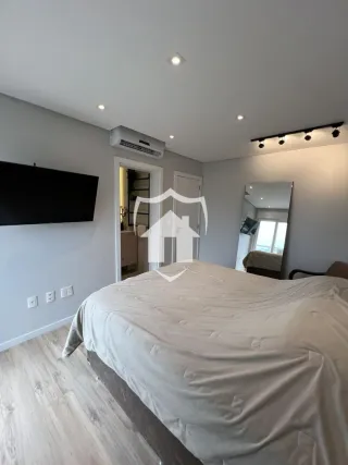 Quarto com cama e televisão na parede em um imóvel.
