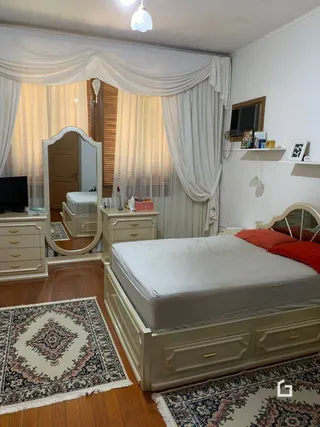 Quarto com cama e cortinas brancas.