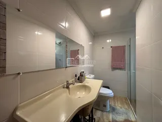 Banheiro com revestimento branco e bancada de pia clara.
