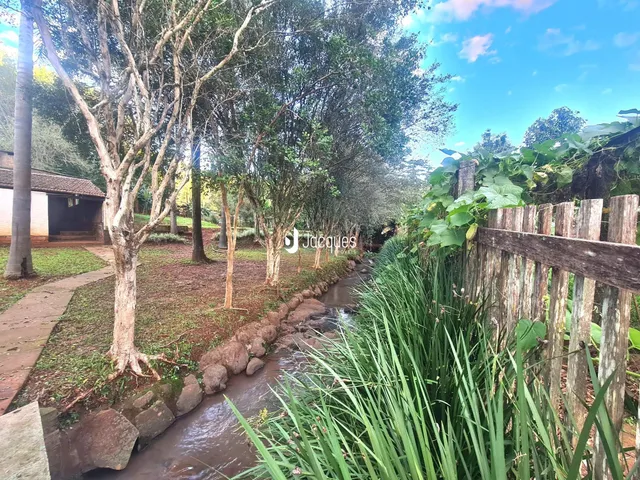 Paisagem de um riacho e vegetação ao lado de uma cerca de madeira.