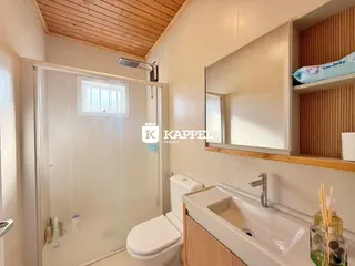 Um banheiro com box de vidro, vaso sanitário e pia.