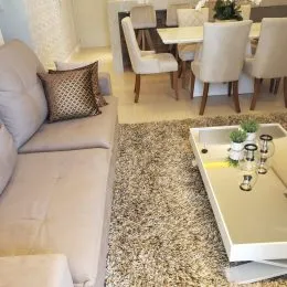 Sala de estar com sofá claro e piso de carpete.