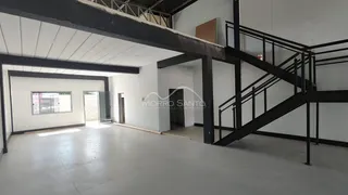 Foto de um espaço interno com estrutura de concreto aparente e escadaria metálica.