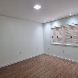 Foto de um cômodo interno com paredes brancas e piso de madeira.