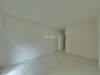 Ambiente interno de uma sala ampla com paredes brancas e piso claro.