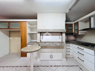 Vista interna de uma cozinha com bancada de granito e armários brancos.