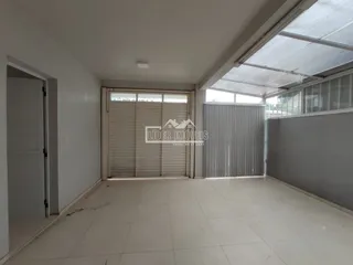 Vista interna de um ambiente com piso de cerâmica e porta de garagem.