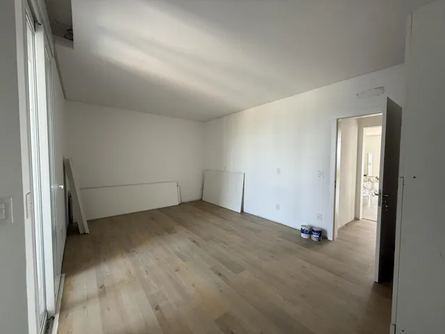 Sala de estar com piso de madeira clara e paredes brancas.