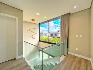 Ambiente interno com vista para o exterior e guarda-corpo de vidro.
