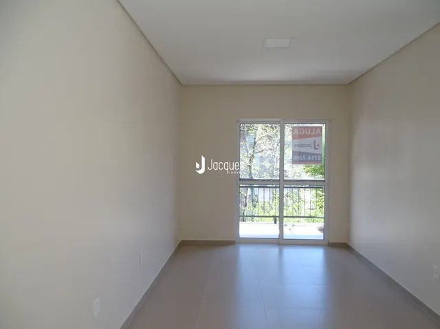Interior de uma sala de estar com paredes brancas e piso claro.