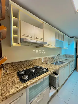 Cozinha com armários claros e bancadas de granito.
