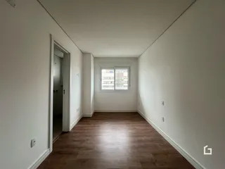 Hall de corredor com piso de madeira e paredes brancas.