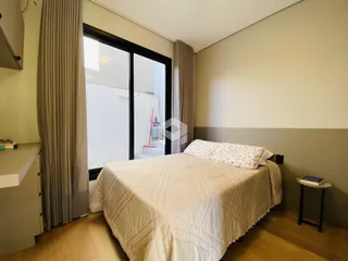 Quarto com grande janela e cortinas em ambiente claro.