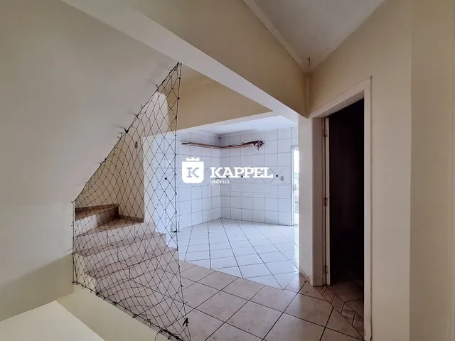 Hall de entrada com escadaria e piso cerâmico em um imóvel.