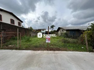 Fachada de uma residência em Lajeado, Brasil, com vegetação e cerca na frente.