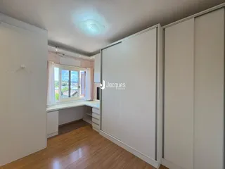 Ambiente interno com piso de madeira e armários brancos.